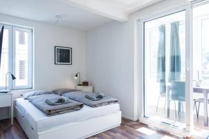 a white bedroom with a bed and a window at HITrental Wiedikon Apartments in Zurich