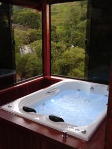 uma banheira num quarto com uma janela em Chalés Pedacim du Céu em Bueno Brandão