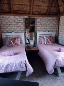 a bedroom with two beds with purple blankets and a mirror at Slypsteen Guest Farm in Sternham