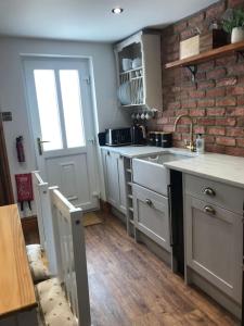 a kitchen with white cabinets and a brick wall at Cosy Bay Cottage in Scarborough