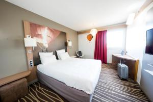 um quarto de hotel com uma cama grande e uma janela em Mercure Vienne Sud Chanas em Chanas