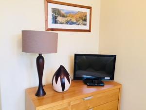 een televisie en een lamp op een houten dressoir bij Salisbury Guest House in Keswick