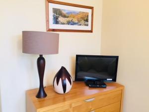 a television and a lamp on top of a wooden dresser at Salisbury Guest House in Keswick