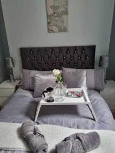 a bed with a table with a tray on it at Serene getaway Apartments in Maidstone