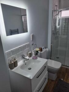 a white bathroom with a sink and a shower at Serene getaway Apartments in Maidstone