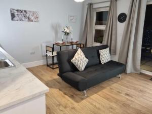 ein Wohnzimmer mit einem schwarzen Sofa und einem Tisch in der Unterkunft Serene getaway Apartments in Maidstone