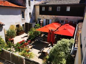un patio con sombrilla roja, sillas y flores en Hôtel Restaurant Le Lion d'Or, en Gémozac
