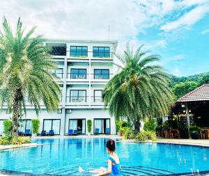 uma mulher sentada numa piscina em frente a um edifício em KEP BAY HOTEL & RESORT em Kep