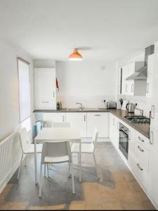 uma cozinha branca com uma mesa e cadeiras brancas em Anox serviced apartment em Newcastle upon Tyne