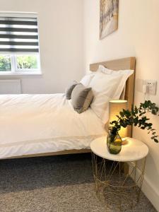 a bed with white sheets and pillows and a table at Spacious En-suite Private Double Bedroom in Oxford