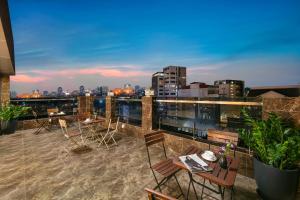 un patio en la azotea con mesas y sillas en un edificio en Nesta Boutique Hotel Hanoi en Hanói