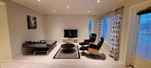 ein Wohnzimmer mit einem Sofa, Stühlen und einem TV in der Unterkunft ANDY - Perfect location in the heart of Närpes 75 m2 - Sauna - Built in 2023 in Närpiö