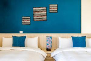 two beds in a room with a blue wall at Millet's House in Taitung City +25 photos