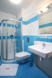 a blue and white bathroom with a sink and a shower at Penzion Morava in Otrokovice