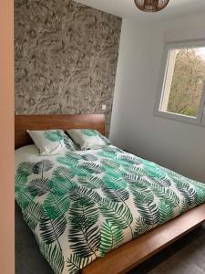 łóżko z zieloną i białą kołdrą i oknem w obiekcie Gîte Zen Lonora w mieście Créhange