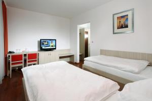 una camera d'albergo con due letti e una televisione di Penzion Morava a Otrokovice