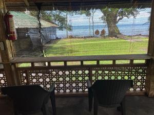 a screened in porch with two chairs and a view of the ocean at Borbon's Treehouse By the Sea in Mambajao