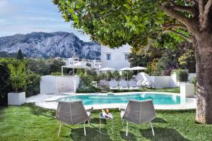 a garden with a pool and chairs and a house at Pazziella Garden & Suites in Capri