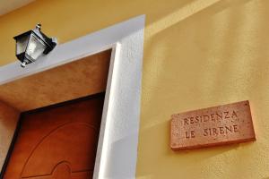 a sign on the side of a building with a door at Residenza Le Sirene in Santa Domenica