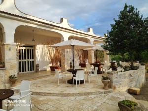 un patio con mesa, sillas y sombrillas en Le Corti del Casale, en Alberobello