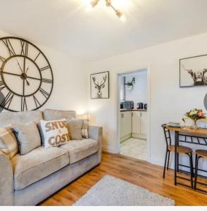 a living room with a couch and a clock on the wall at Bernards Hill in Bridgnorth