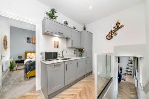 a kitchen with white cabinets and a living room at Finest Retreats - The Bank House in Boroughbridge