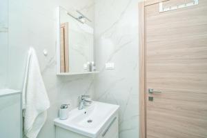 La salle de bains blanche est pourvue d'un lavabo et d'un miroir. dans l'établissement Apartment Zoric, à Dubrovnik