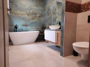 a bathroom with a tub and a sink and a toilet at Penzion Siesta in Valtice