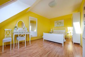 a bedroom with yellow walls and a bed and a desk at Apartamenty Sun & Snow Latarnia in Władysławowo