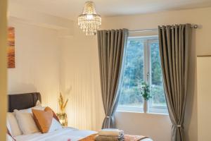 a bedroom with a bed and a window with a chandelier at Ashview 2 - Heathrow - Thorpe Park - Free Parking in Staines