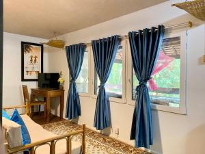 Habitación con cortinas azules, cama y escritorio. en Cozy Paradise en Battambang