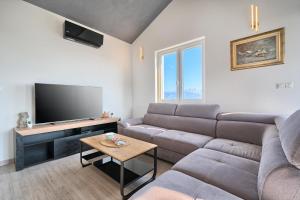 een woonkamer met een bank en een flatscreen-tv bij Aquamarin - Premium Seaview Apartment in Slatine
