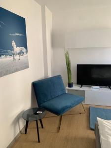 a living room with a blue chair and a tv at Focus Max in Miercurea-Ciuc