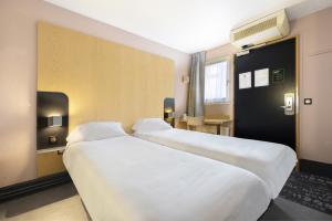 2 camas en una habitación de hotel con sábanas blancas en B&B HOTEL Perpignan Sud Porte d'Espagne en Perpiñán