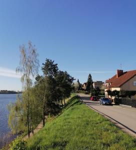 a road next to a body of water with a house at Apartament Wschód Słońca Olecko in Olecko