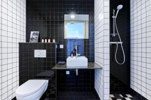 Baño de azulejos negros con aseo y lavamanos en Hello I'm Local - Boutique Hostel, en Haarlem