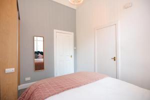 a white bedroom with a bed and a mirror at Dalmeny Street Apartment in Edinburgh