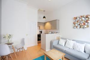 ein Wohnzimmer mit einem Sofa und einem Tisch sowie eine Küche in der Unterkunft Dalmeny Street Apartment in Edinburgh