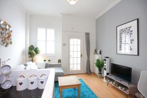 a white living room with a couch and a tv at Dalmeny Street Apartment in Edinburgh