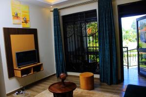 sala de estar con TV y puerta con ventana en Mamikki Farm and Cottages, en Tororo