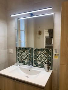 ein Badezimmer mit einem Waschbecken und einem großen Spiegel in der Unterkunft Cosy Joliette, central, climatisé, 2 chambres, WIFI, Garage in Marseille