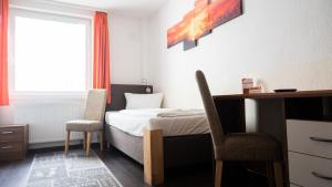 1 Schlafzimmer mit einem Bett, 2 Stühlen und einem Schreibtisch in der Unterkunft Aalreuse in Rostock