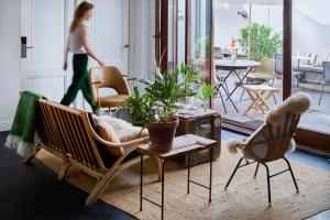 eine Frau geht durch ein Wohnzimmer mit Stühlen und einem Tisch in der Unterkunft Hello I'm Local - Boutique Hostel in Haarlem