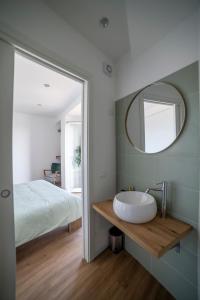 uma casa de banho com um lavatório, uma cama e um espelho. em Vista d’amare em Pozzallo