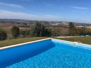 a blue swimming pool with a view of the countryside at Casa do Horizonte in Bombarral