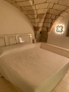 a bedroom with a white bed with a stone wall at Wonderful residence in the heart of Otranto. in Otranto