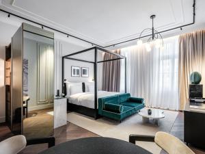 ein Hotelzimmer mit einem Bett und einem grünen Sofa in der Unterkunft The Amauris Vienna - Relais & Châteaux in Wien
