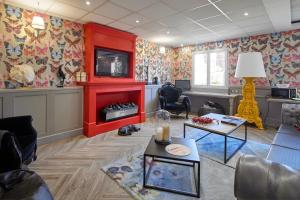 B&B HOTEL Saint-Maur Créteil في سان مور دي فوس: غرفة معيشة مع ورق جدران ملونة ومدفأة حمراء