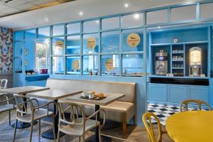 a restaurant with blue walls and tables and chairs at B&B HOTEL Saint-Maur Créteil in Saint-Maur-des-Fossés