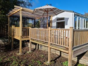 eine Terrasse mit einem Regenschirm und einem Haus in der Unterkunft Riverside Cabin at Pen-Y-Bont Mill in Oswestry